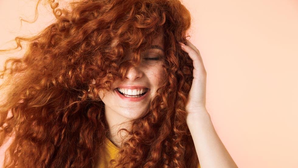 Nahaufnahme einer glücklichen jungen Frau mit langem, geschmeidig roten Haar